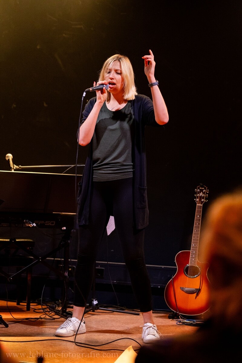 Sängerin Sarah Kaiser - Sarah Singt. Eine Frau steht auf der Bühne mit Mikrofon in der Hand und singt.